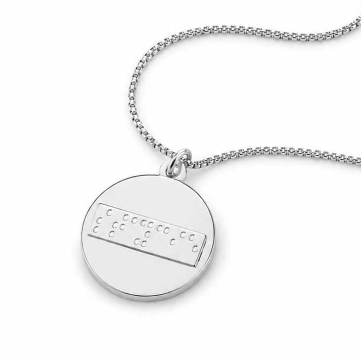 Silver Braille disc necklace showcasing custom engraved characters