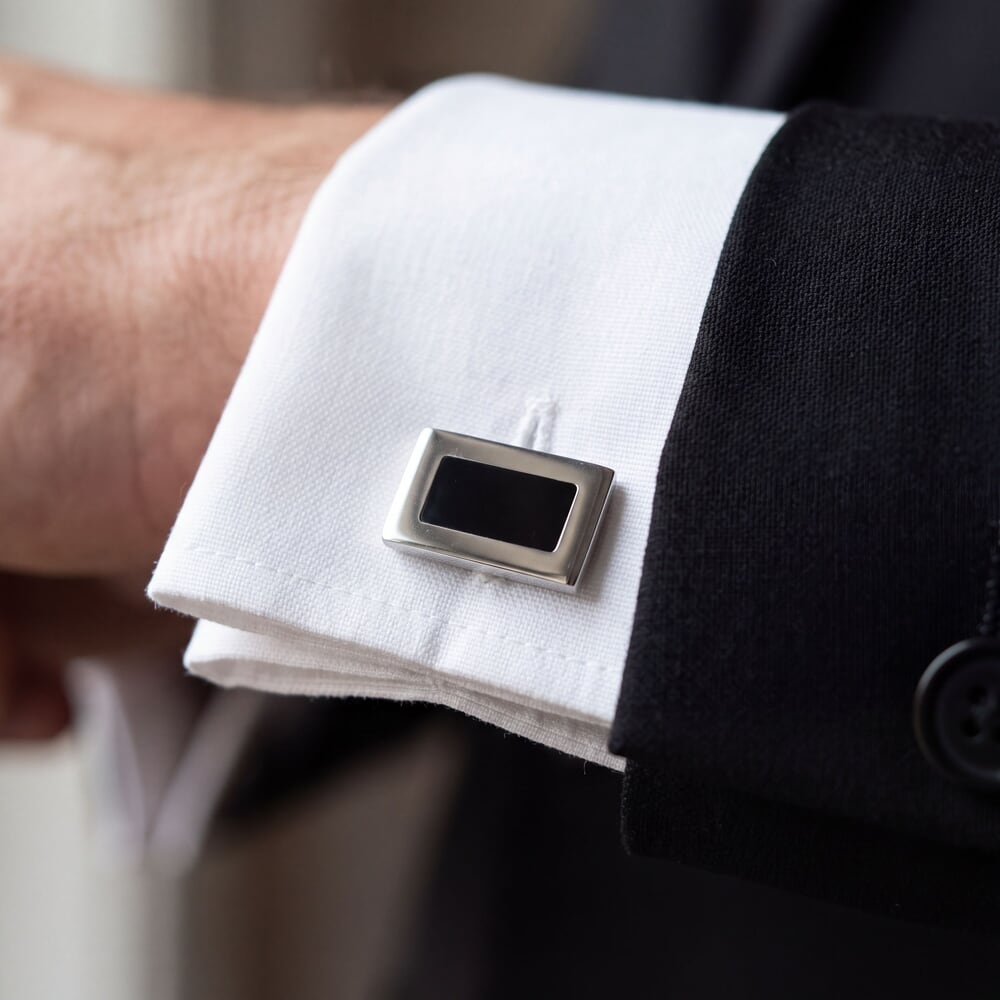 Stylish black cufflinks on a man's cuff, ideal for adding flair to formal attire.