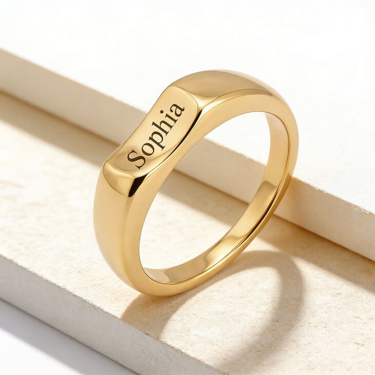 Model wearing a personalized curved signet ring engraved with Sophia against a clean, subtle background
