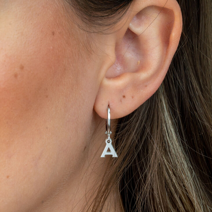 Model adorned with a modern single dangle earring showcasing the letter A, enhancing her outfit.