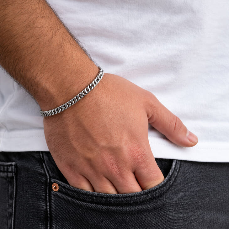 Silver Cuban link bracelet showcased on a wrist near a man's pocket