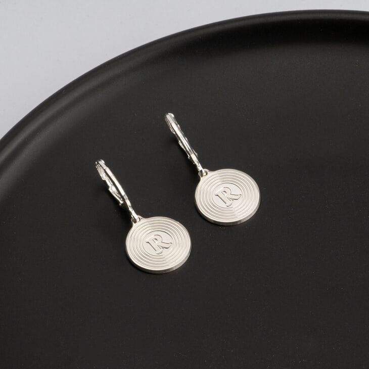 Elegant circle earrings featuring initial R presented on a sleek plate