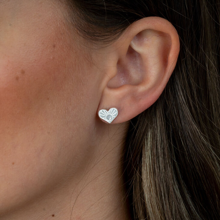Close-up of diamond heart earrings worn by model, showcasing stylish design