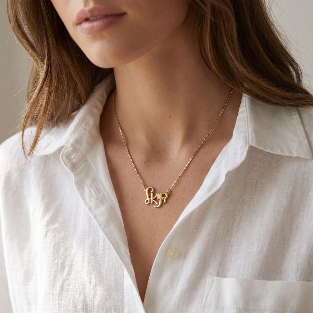 Model elegantly displays Hebrew name necklace in flowing Ahava script, styled with a crisp white shirt.