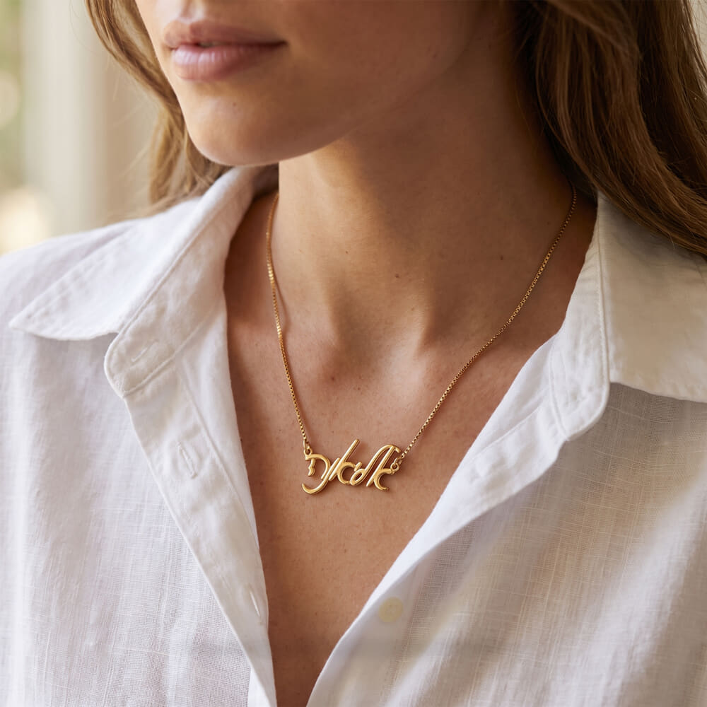 Woman highlights the Elegant Hebrew Script Name Necklace with an elegant outfit.