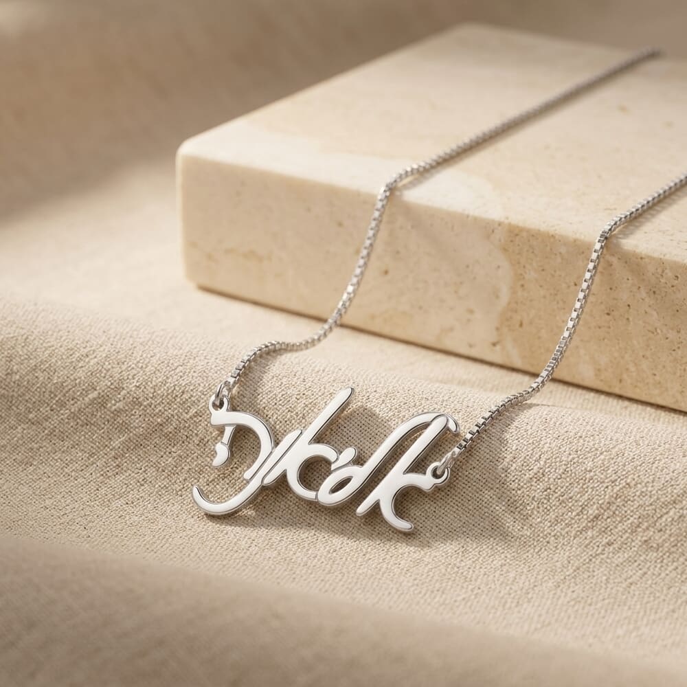 Woman highlights the Elegant Hebrew Script Name Necklace, paired with a warm-toned setting.
