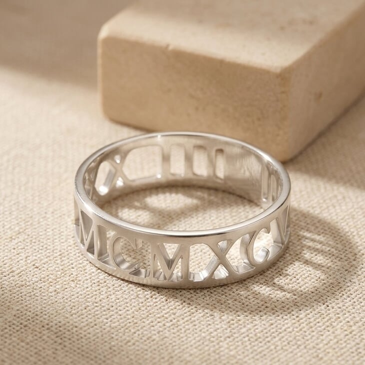 Mens Roman Numeral Ring displayed on a textured surface, revealing detailed engravings