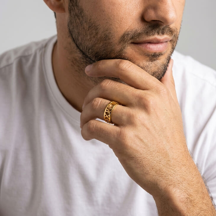 Man in a casual tee with a Custom Men's Roman Numeral Ring, resting chin on hand