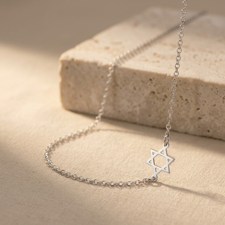 Silver Sideways Star of David Necklace highlighted on a light, textured background