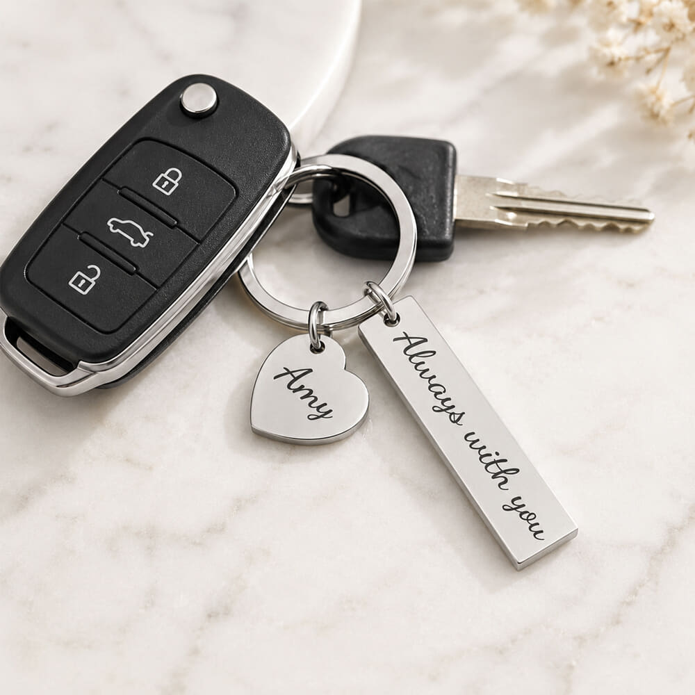 The Personalized Heart & Bar Keychain is worn by a model with keys on a chic marble surface
