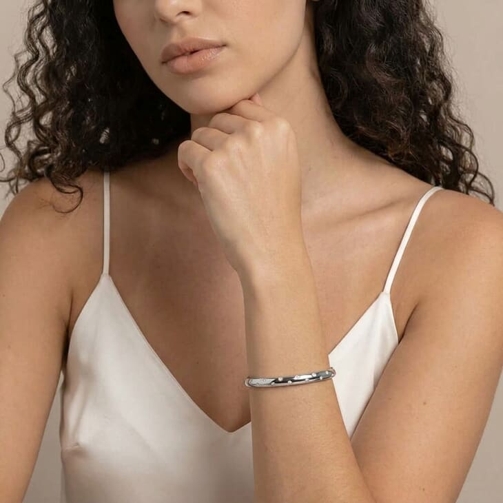 Woman highlighting the Celestial Star cuff bracelet, featuring its polished look on a plain surface