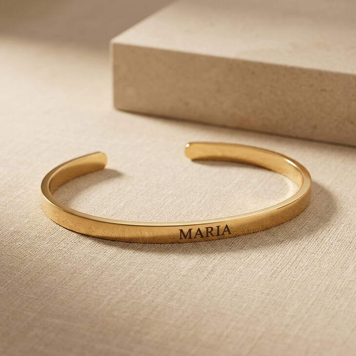 Thin Open Bangle Bracelet with custom engraving 'MARIA' on a subtle fabric surface