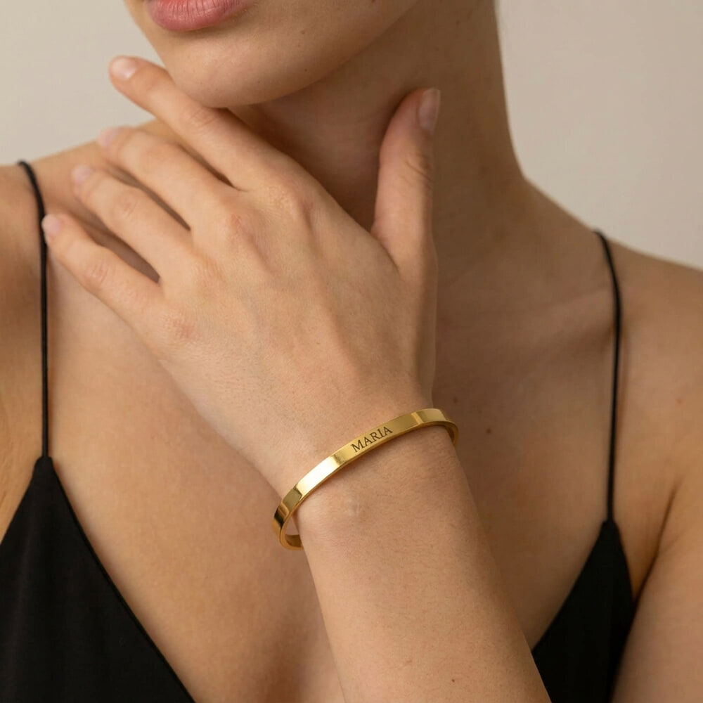 Woman modeling a thin open bangle bracelet featuring personalized engraving for a chic look