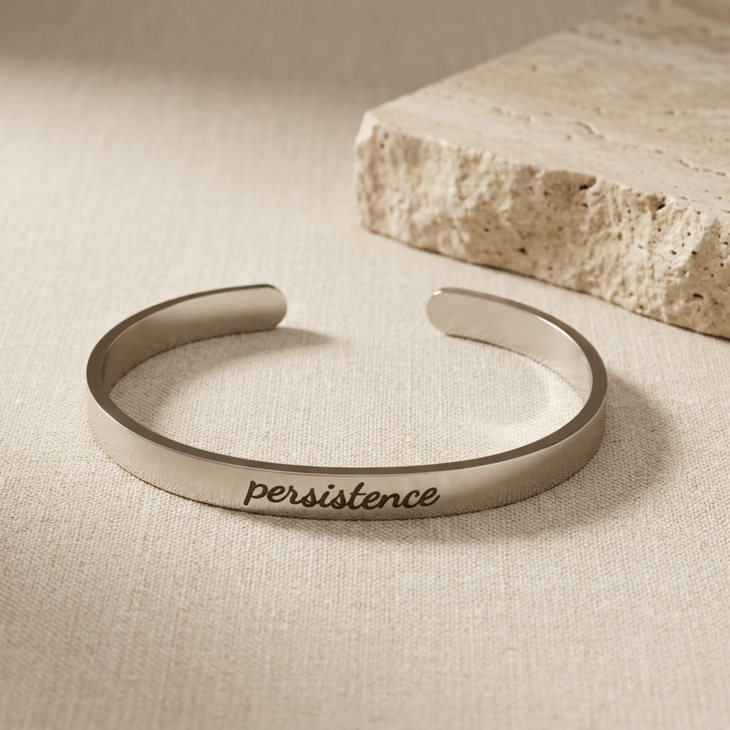Thick silver cuff bracelet showcasing the engraving of 'persistence'