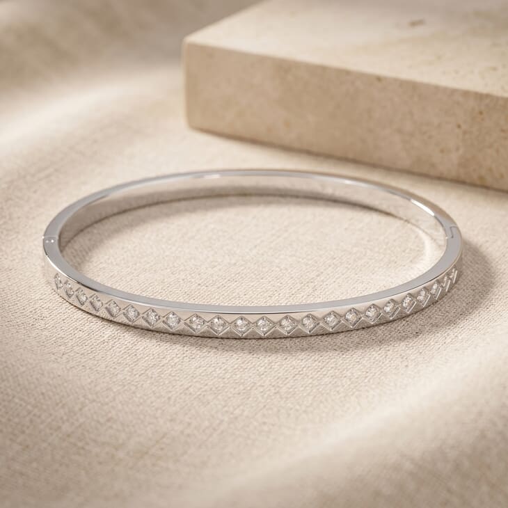 Stylish close-up of a geometric bracelet with cubic zirconia set against linen
