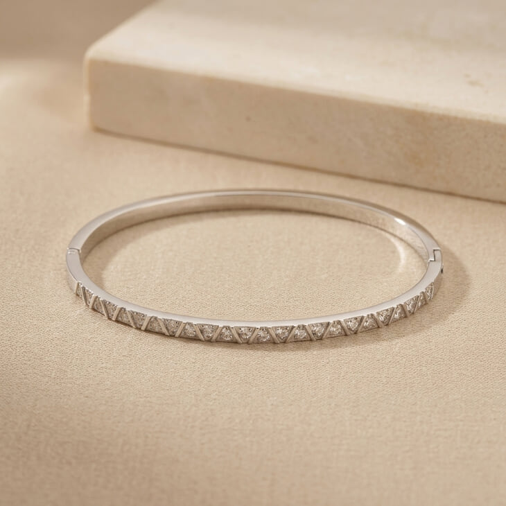 Full Zircon Bangle Bracelet resting on a light fabric, emphasizing its stylish silver appearance