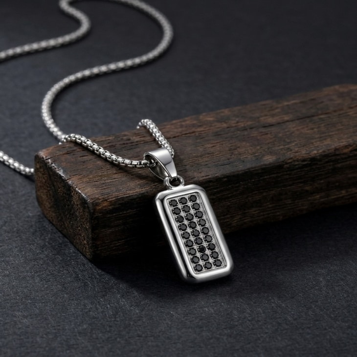 Man displaying Men's Black Zircon Tag Necklace, showcasing the sleek pendant on a dark wooden surface