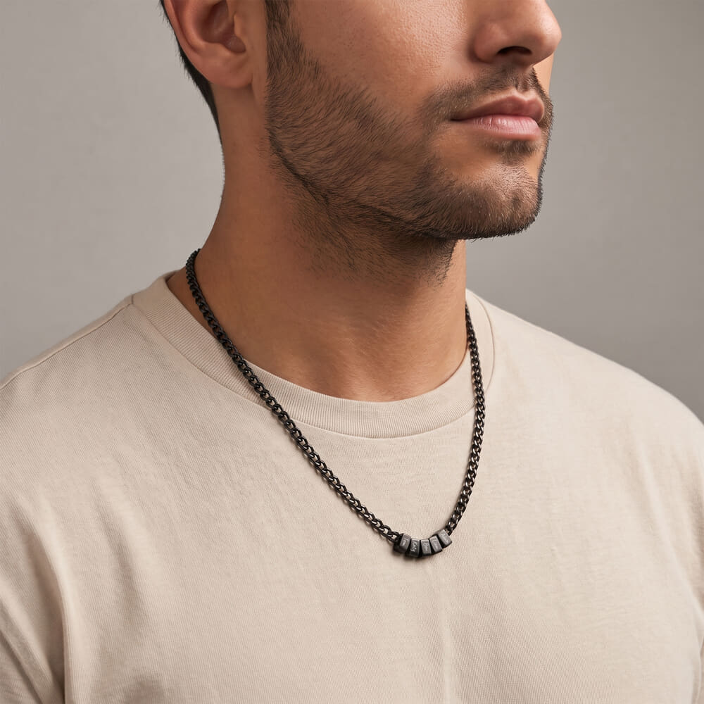Stylish model with a personalized black dad necklace showing engraved names against a simple backdrop