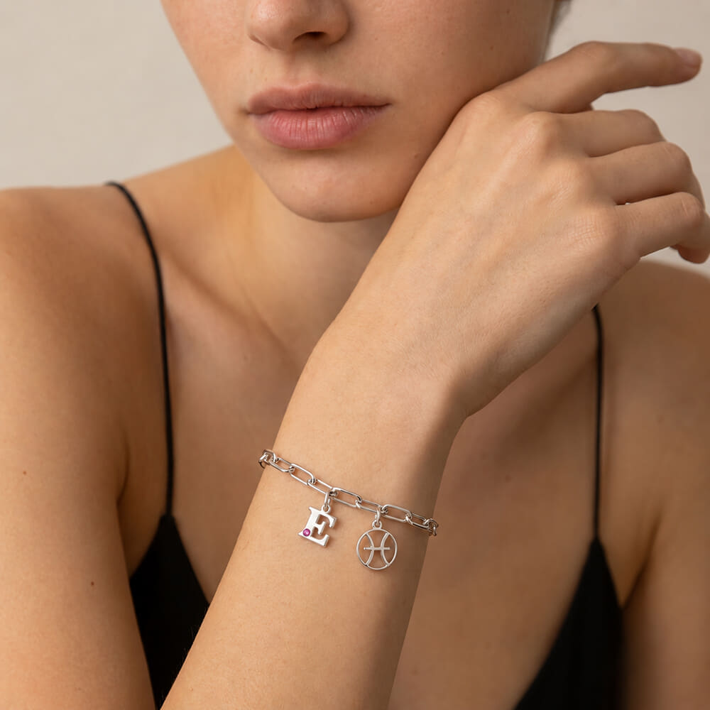 Model elegantly wears Circle Zodiac and Initial Bracelet with pink birthstone detail on wrist