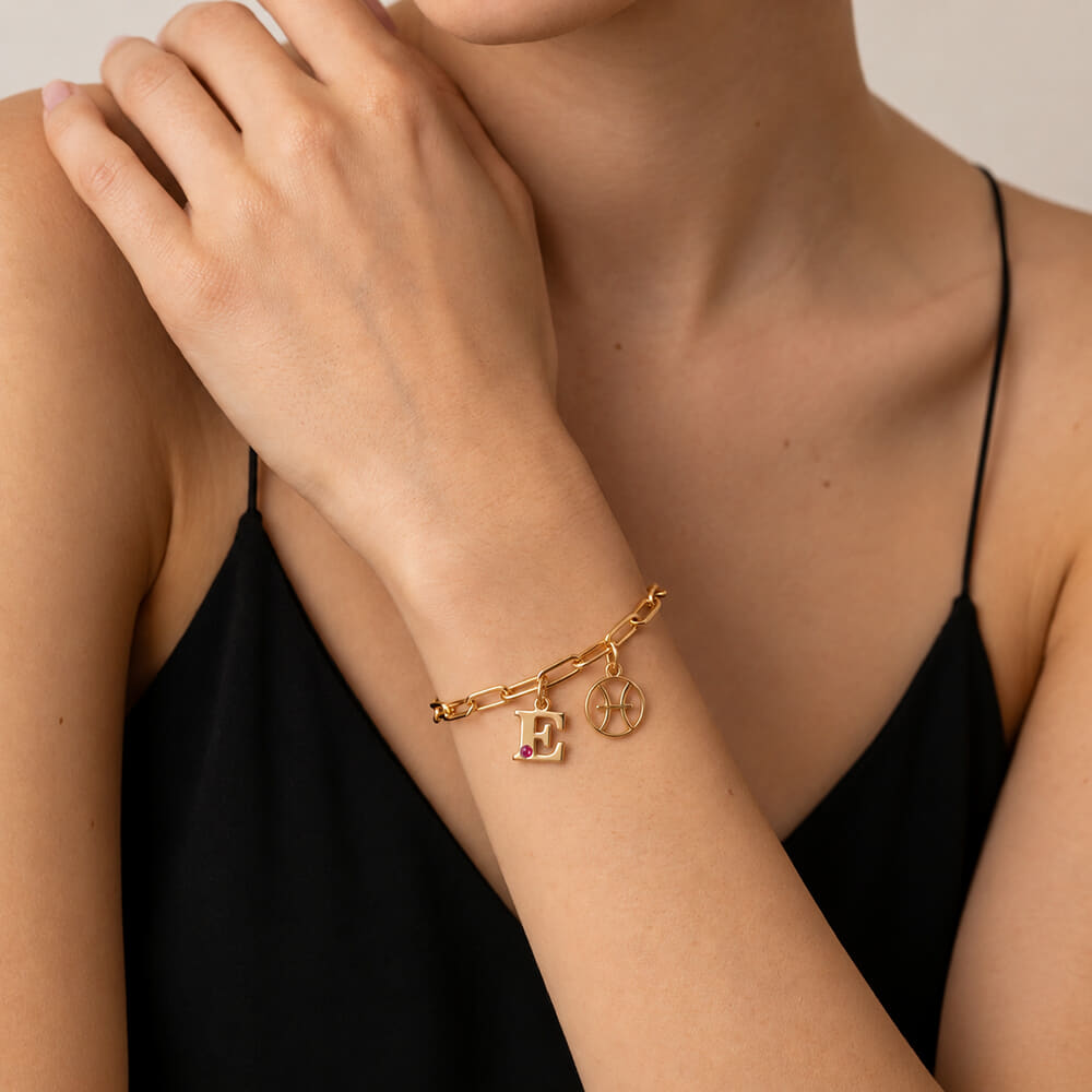 Stylish model flaunts Circle Zodiac and Initial Bracelet with red birthstone accent on wrist