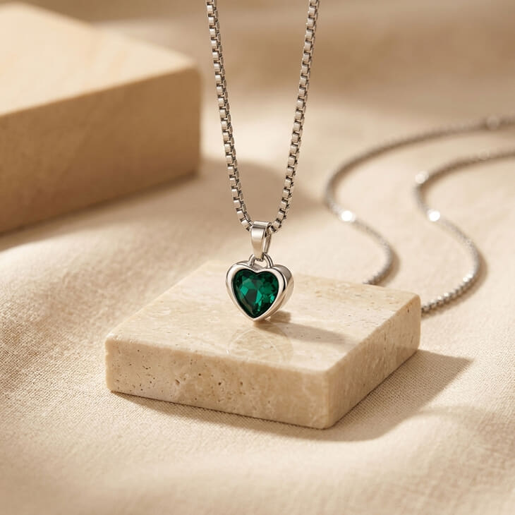 Heart pendant necklace highlighted by a stunning green gemstone on a soft backdrop